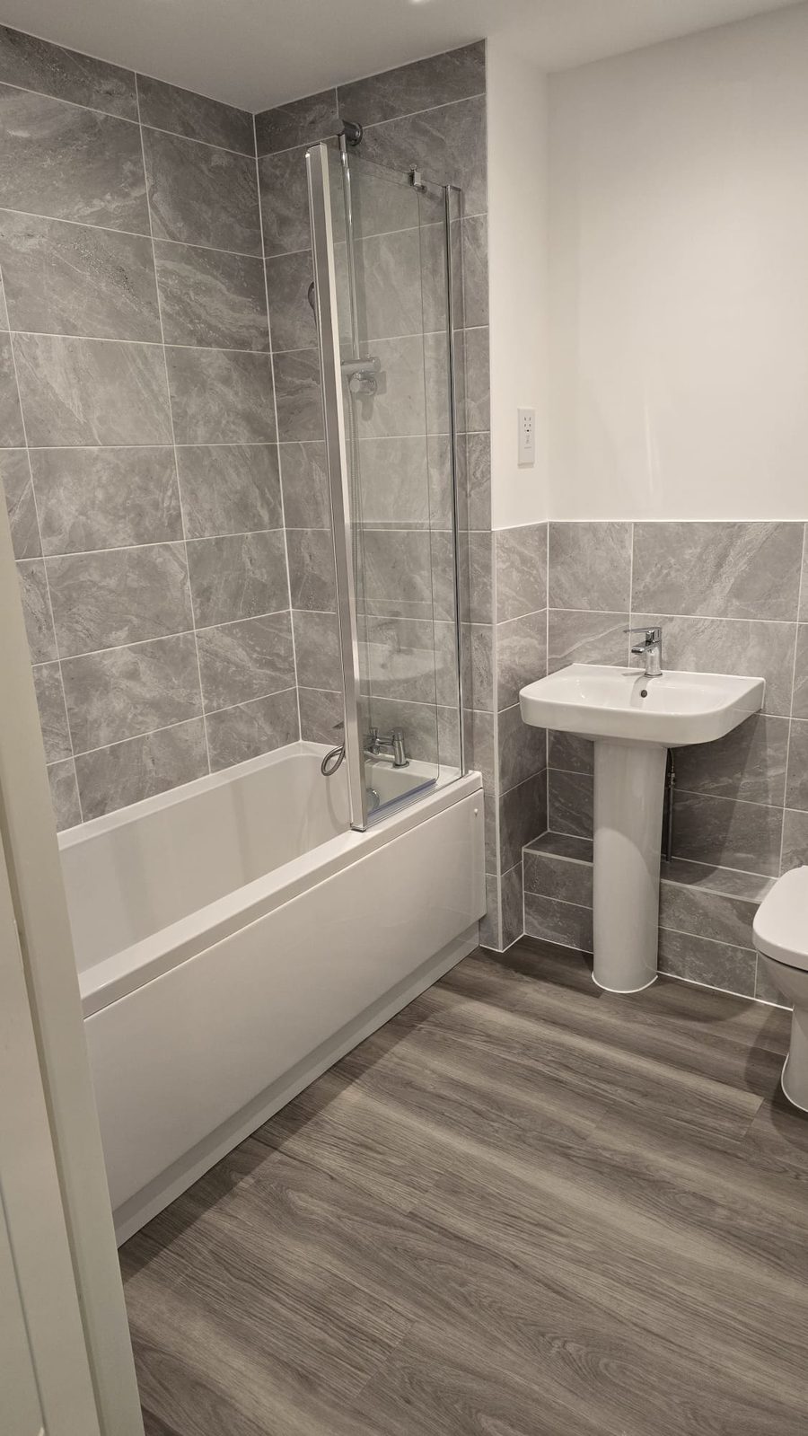 Bathroom with tiled walls, bath and basin after a full clean